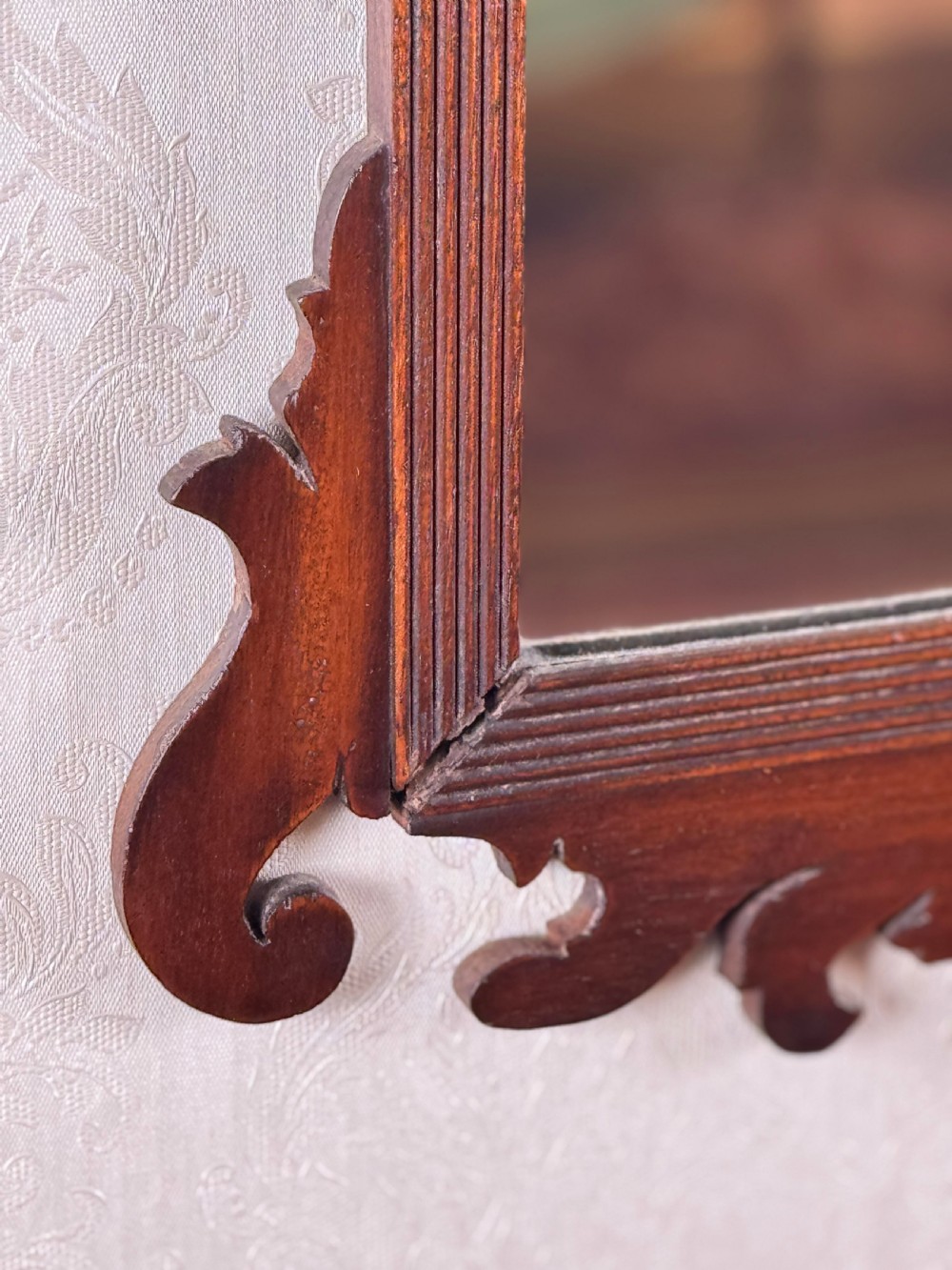 A mahogany Chippendale style wall mirror featuring intricate fretwork scrollwork on the top crest and bottom apron. View II