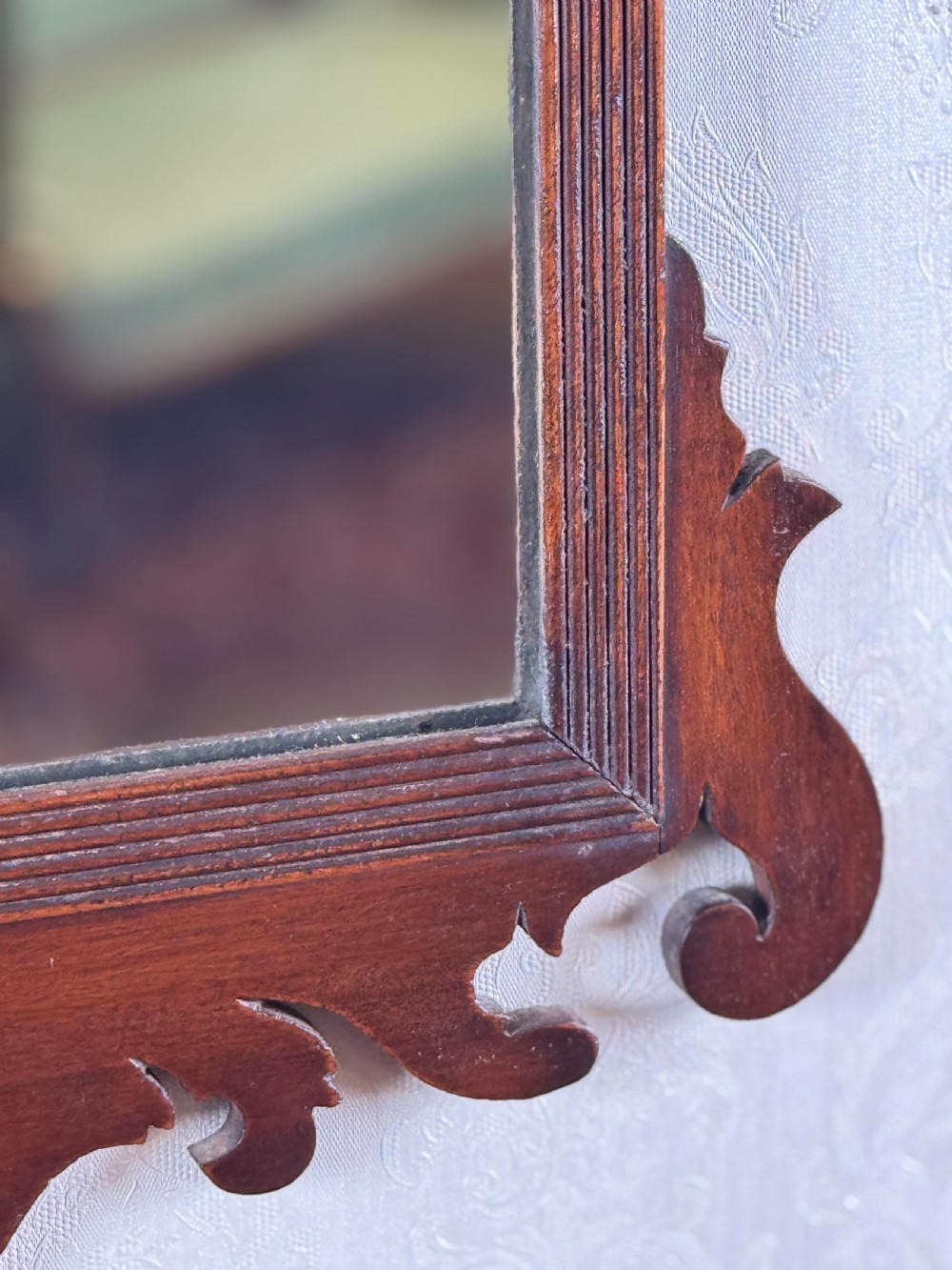 A mahogany Chippendale style wall mirror featuring intricate fretwork scrollwork on the top crest and bottom apron. View III