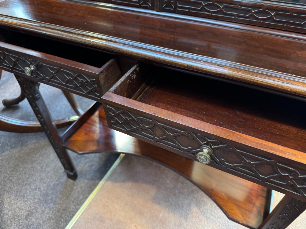 A Chippendale style dark mahogany display cabinet featuring a broken pediment top, geometric astragal glazed double doors, blind fretwork carving, and a lower shelf on square legs. View IV