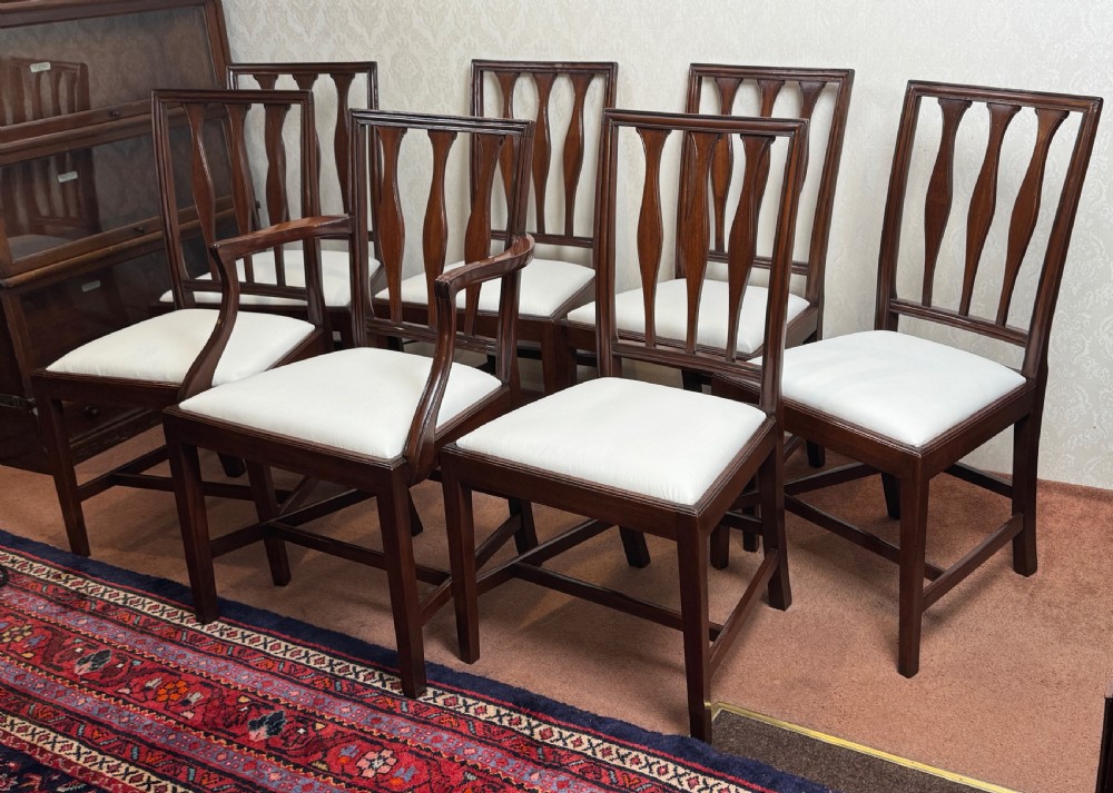 A set of seven mahogany dining chairs with carved vertical splat backs, including six side chairs and one carver armchair with cream fabric seats. View II