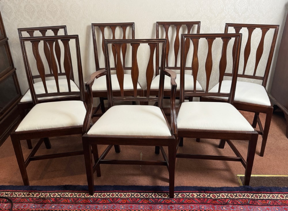 A set of seven mahogany dining chairs with carved vertical splat backs, including six side chairs and one carver armchair with cream fabric seats. View III
