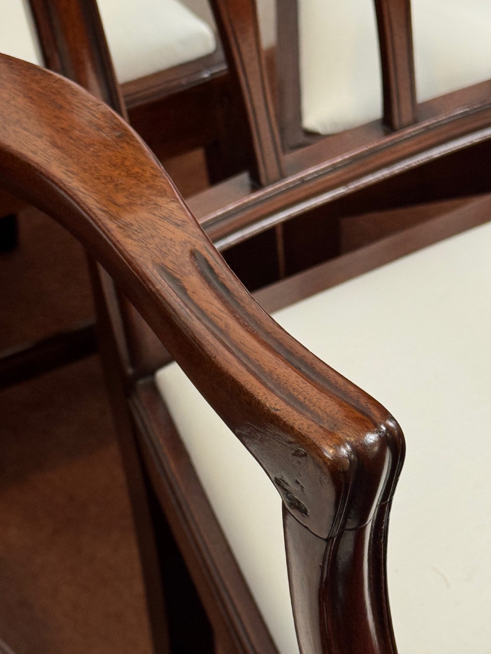 A set of seven mahogany dining chairs with carved vertical splat backs, including six side chairs and one carver armchair with cream fabric seats. View IV