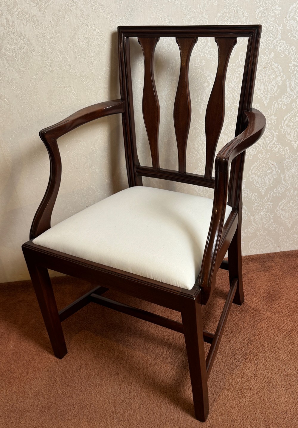 A set of seven mahogany dining chairs with carved vertical splat backs, including six side chairs and one carver armchair with cream fabric seats. View V