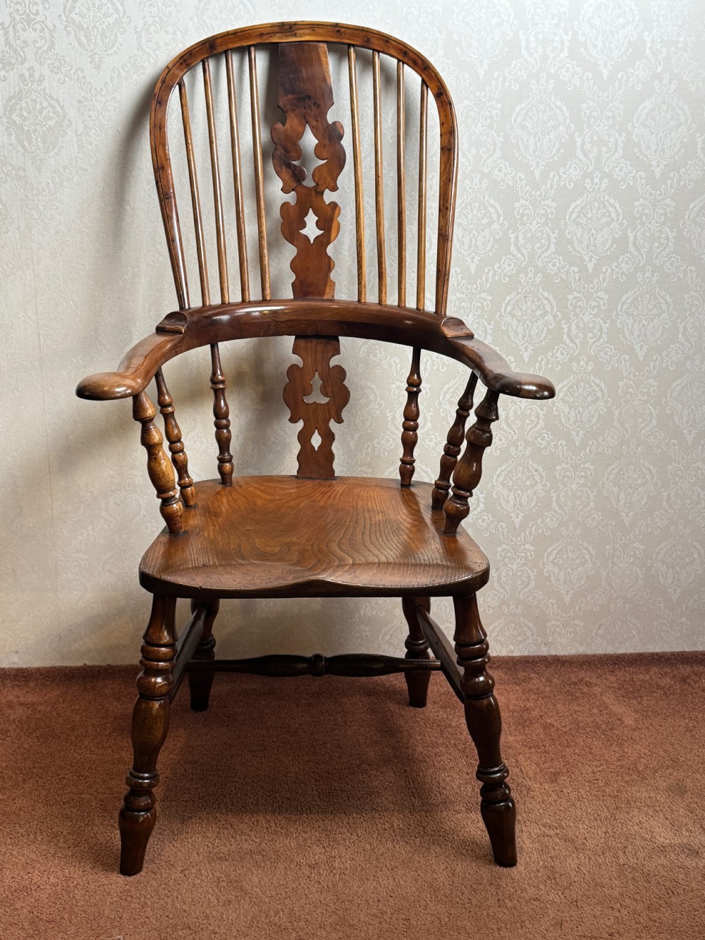 A high back yew wood Windsor armchair featuring an arched hoop back, a pierced central splat, broad curved arms, and turned wooden legs. View II