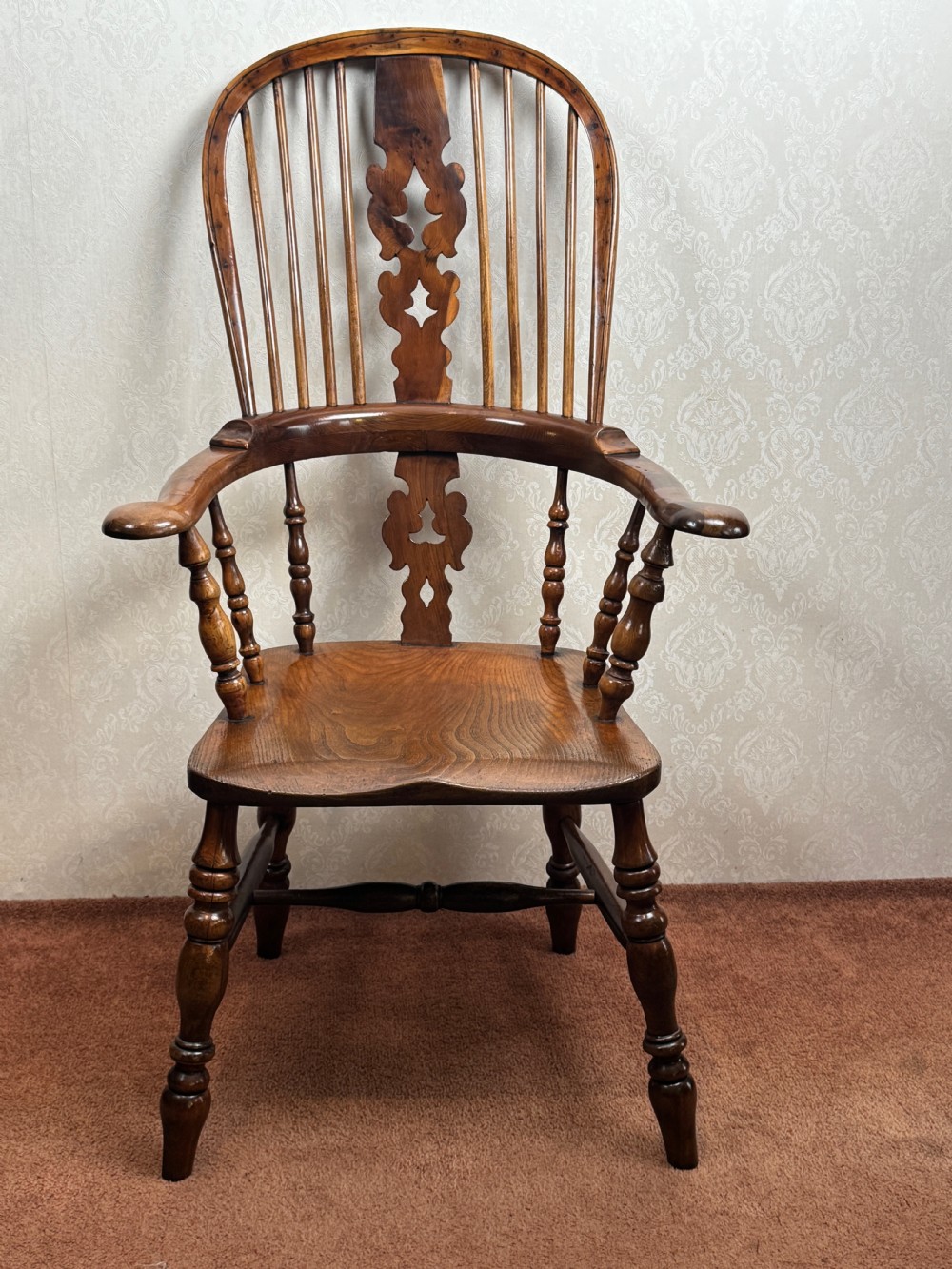A high back yew wood Windsor armchair featuring an arched hoop back, a pierced central splat, broad curved arms, and turned wooden legs. View III