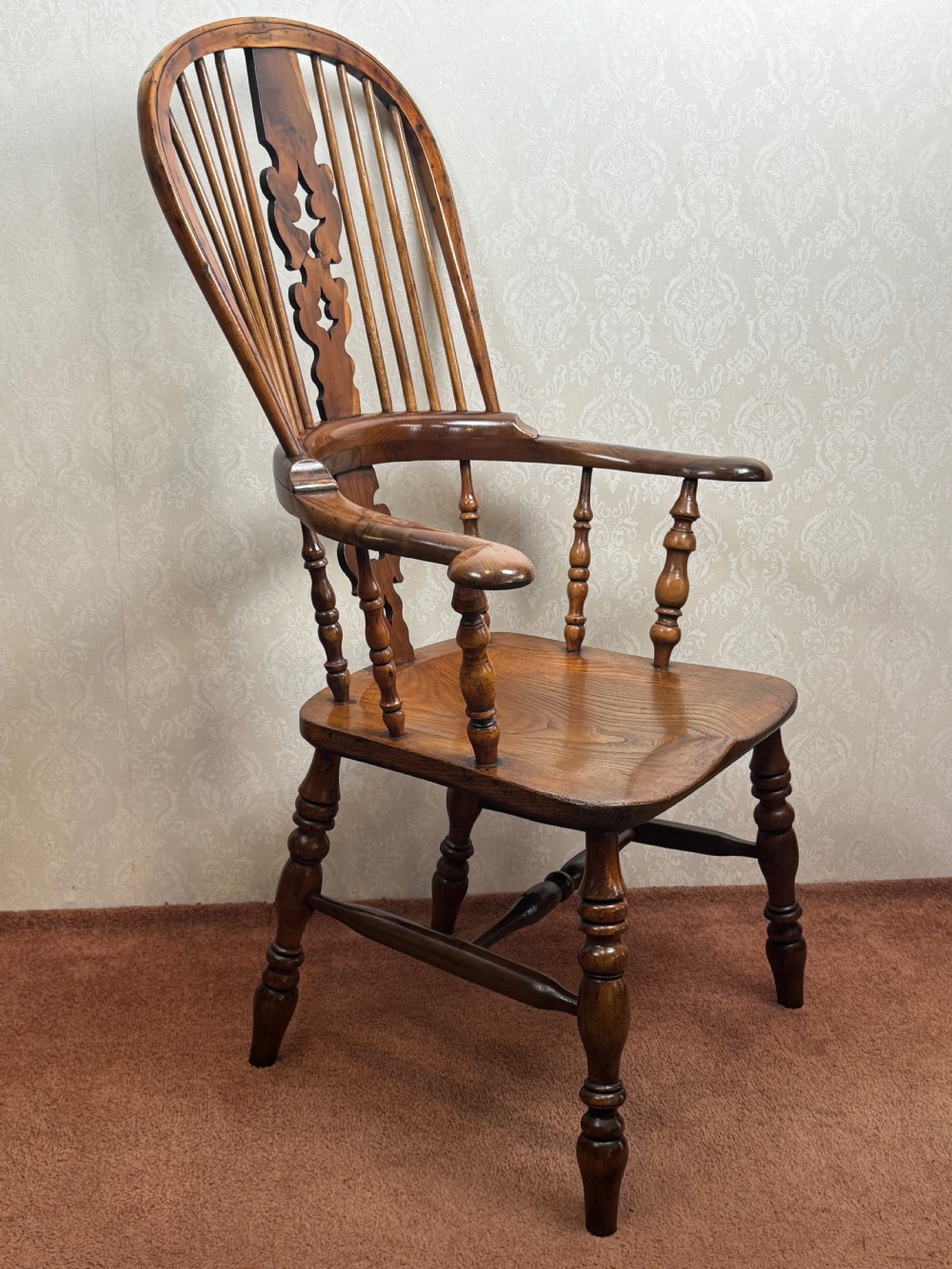 A high back yew wood Windsor armchair featuring an arched hoop back, a pierced central splat, broad curved arms, and turned wooden legs. View IV