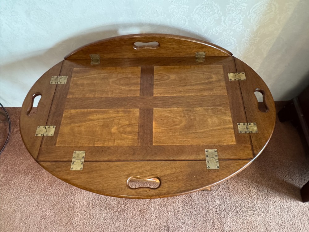 An early nineteenth-century wooden butler tray table featuring a hinged oval top with cutout handles resting on a curved folding X-frame base. View IV