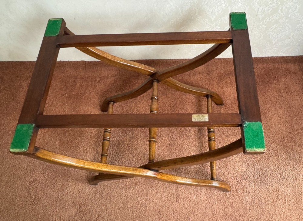 An early nineteenth-century wooden butler tray table featuring a hinged oval top with cutout handles resting on a curved folding X-frame base. View VI