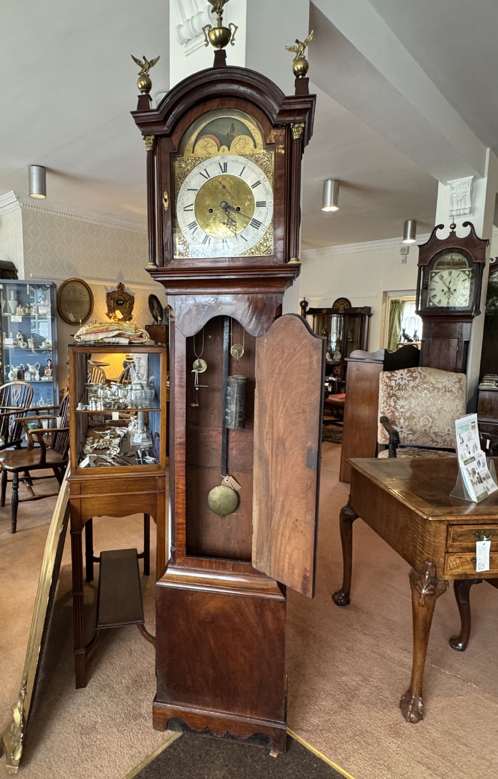 A tall Georgian mahogany longcase clock featuring a swan-neck pediment hood topped with three brass eagle finials and an ornate brass dial. View III