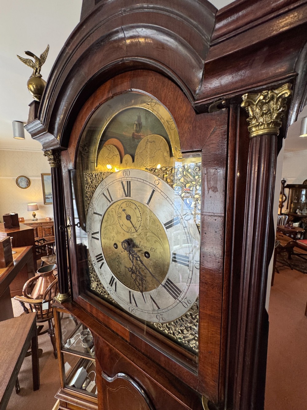 A tall Georgian mahogany longcase clock featuring a swan-neck pediment hood topped with three brass eagle finials and an ornate brass dial. View IV