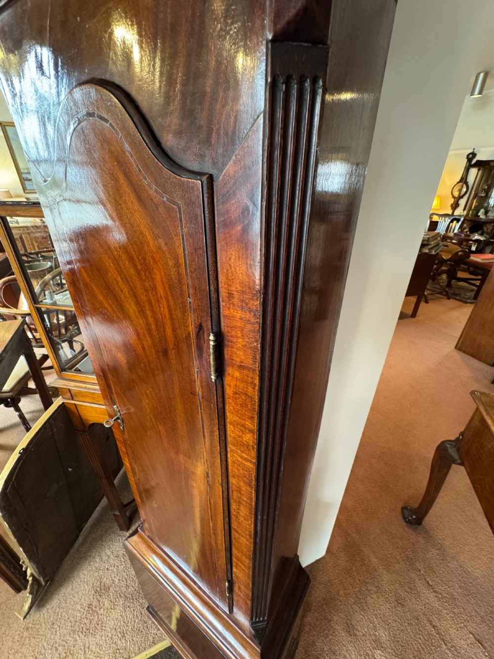 A tall Georgian mahogany longcase clock featuring a swan-neck pediment hood topped with three brass eagle finials and an ornate brass dial. View VIII