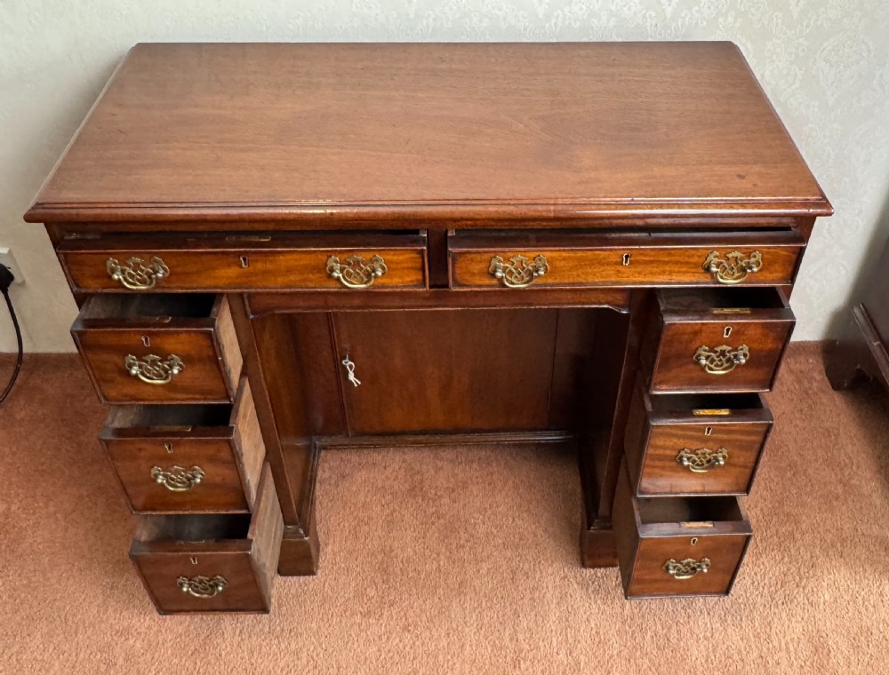 An 18th-century Georgian mahogany kneehole dressing table featuring multiple drawers with brass handles, a central recessed cupboard, and bracket feet. View IV