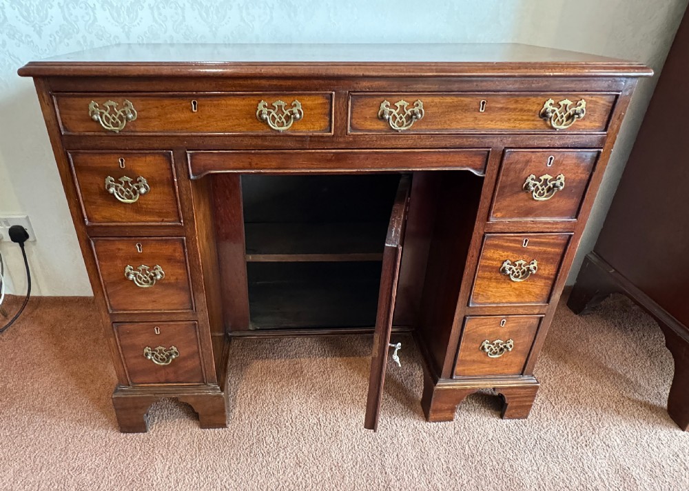 An 18th-century Georgian mahogany kneehole dressing table featuring multiple drawers with brass handles, a central recessed cupboard, and bracket feet. View VI
