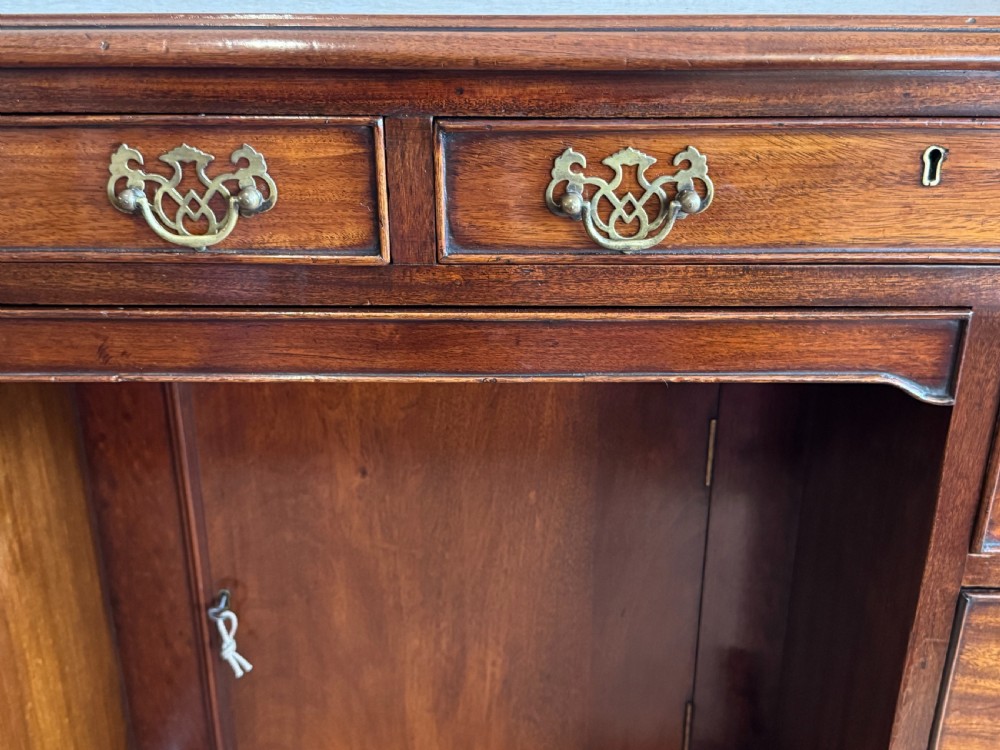 An 18th-century Georgian mahogany kneehole dressing table featuring multiple drawers with brass handles, a central recessed cupboard, and bracket feet. View VII