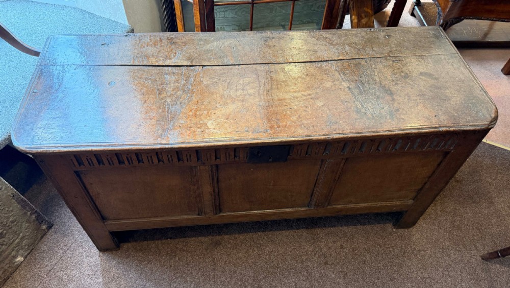 A late 17th-century English oak coffer featuring a three-panel front, a carved upper frieze, a hinged plank top, and a central iron lock plate. View II