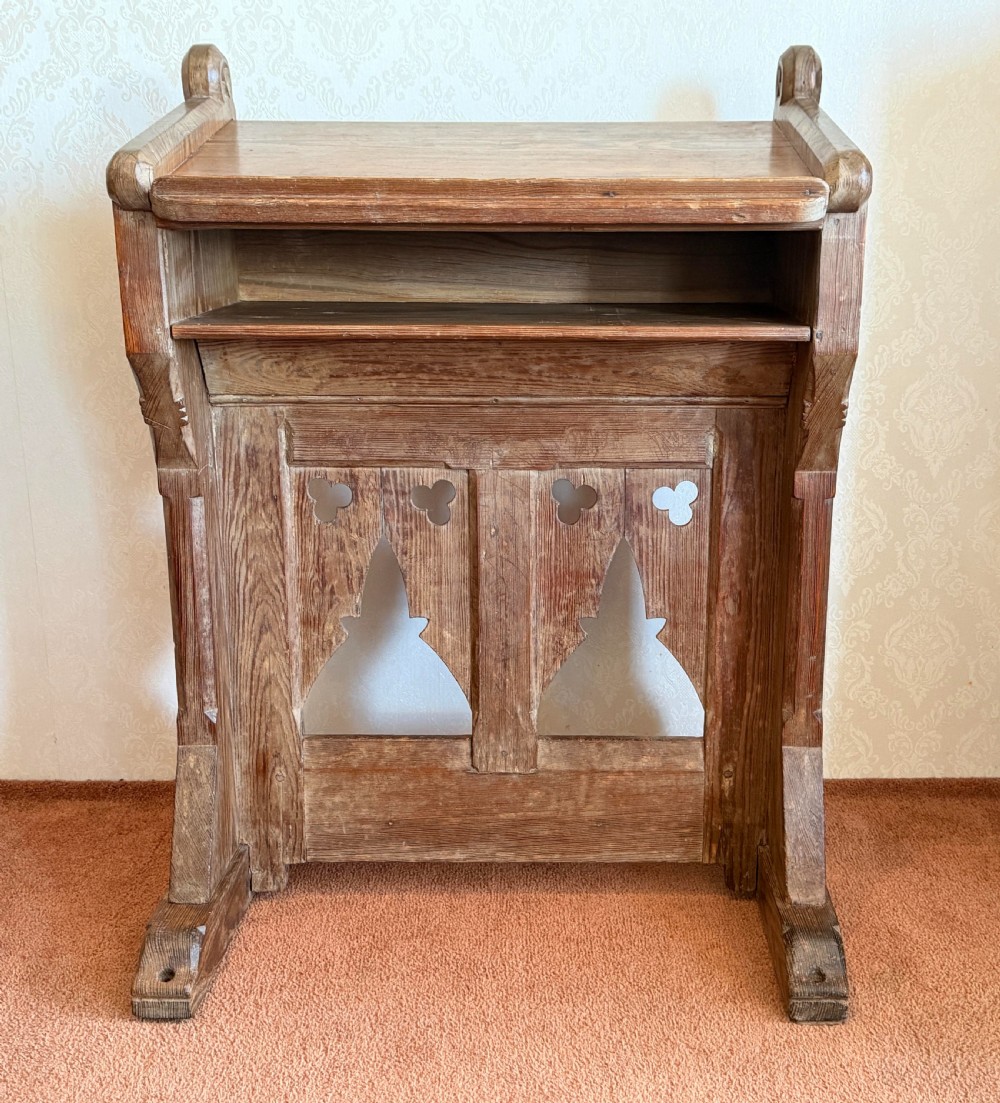 A solid pine Gothic Revival church lectern featuring carved trefoil and lancet arch cutouts, a sloped reading surface, and an open lower shelf. View II
