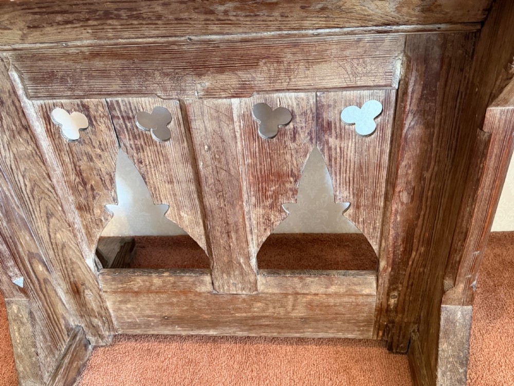 A solid pine Gothic Revival church lectern featuring carved trefoil and lancet arch cutouts, a sloped reading surface, and an open lower shelf. View IV