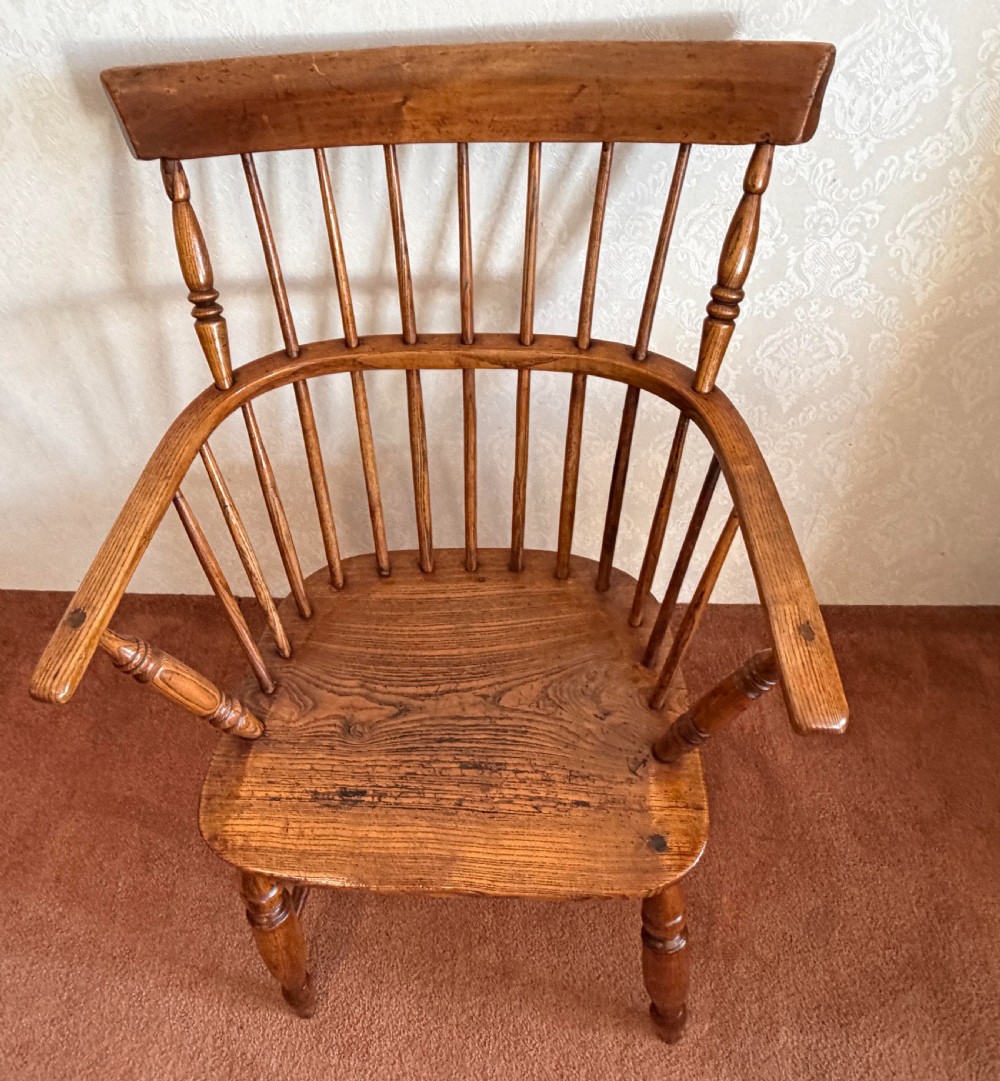 An 18th-century comb-back Windsor armchair made of polished timber with turned legs, a shaped seat, and vertical back spindles. View II