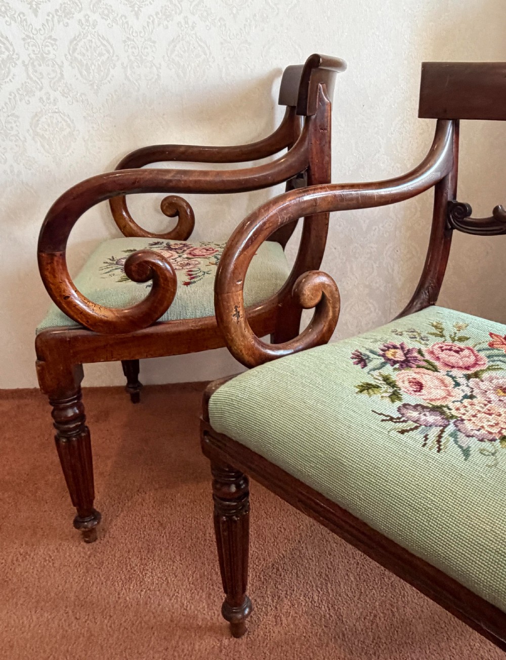 A pair of antique mahogany carver armchairs featuring swept scroll arms, carved central rails, turned fluted front legs, and green needlepoint floral upholstered seats. View VII