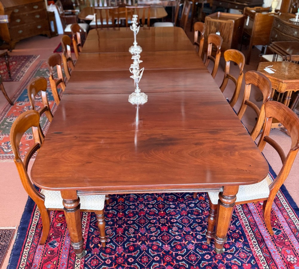 A large mahogany extending dining table with additional inserted leaves, turned legs, and brass castors.