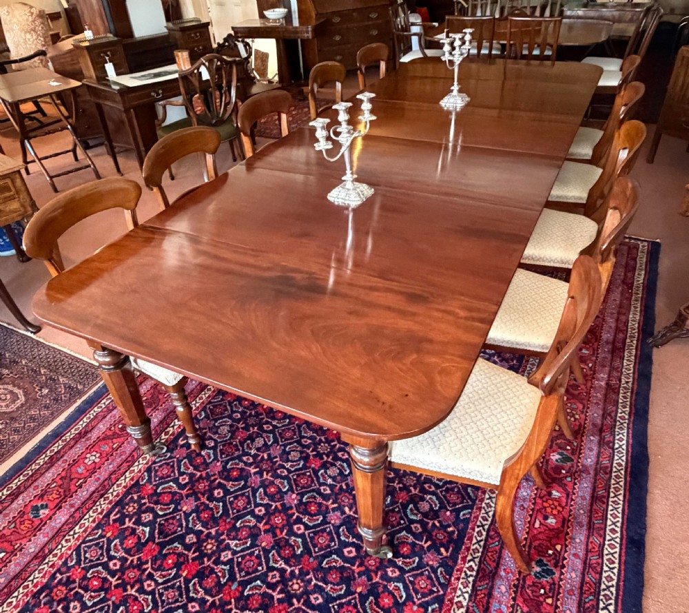 A large mahogany extending dining table with additional inserted leaves, turned legs, and brass castors. View II
