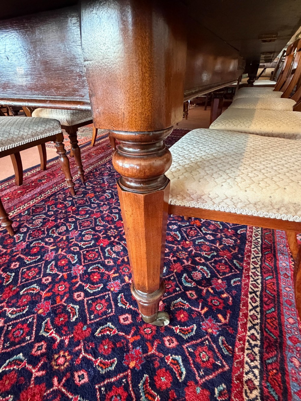 A large mahogany extending dining table with additional inserted leaves, turned legs, and brass castors. View VII