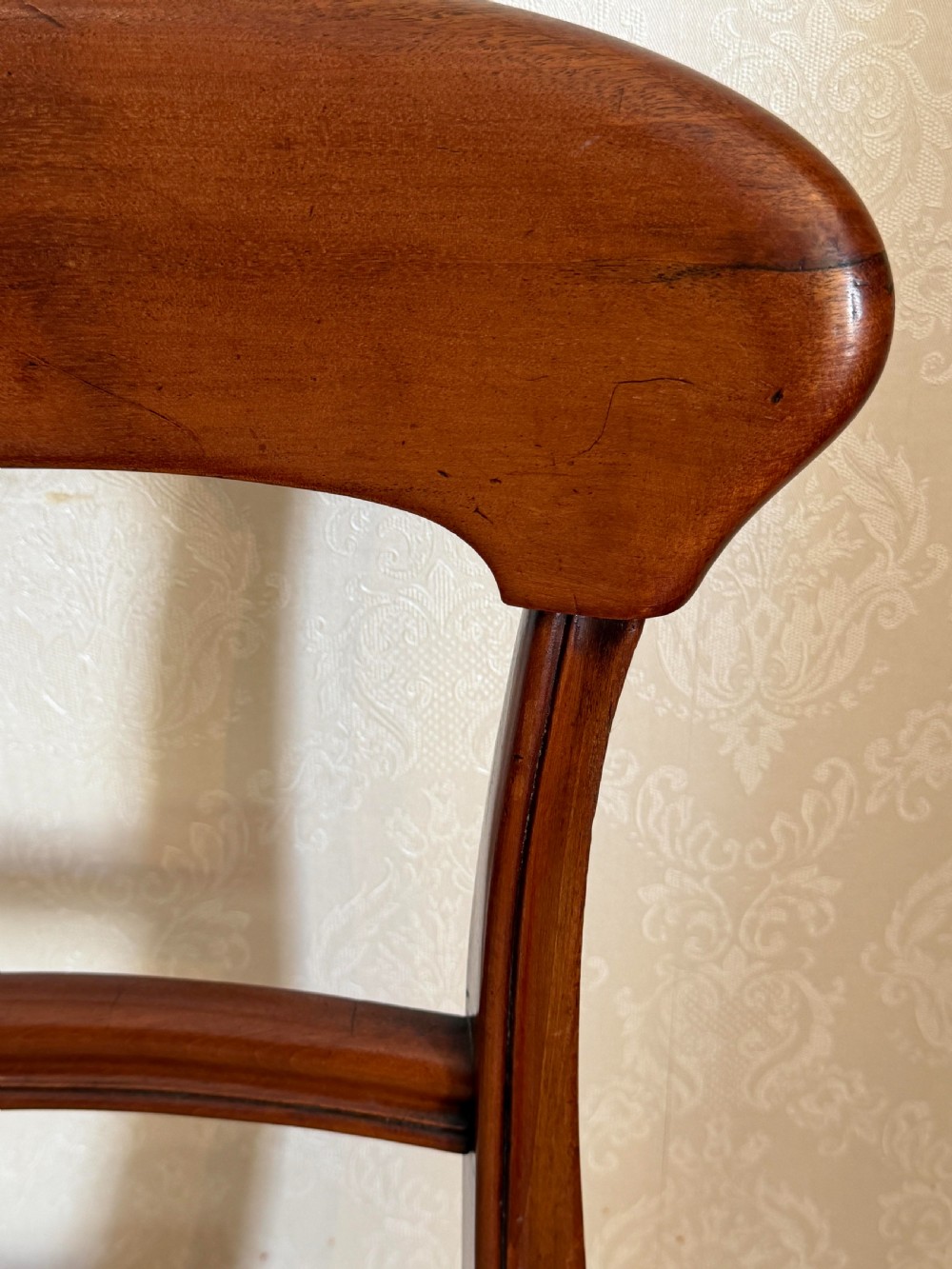 A mahogany dining chair featuring a curved top rail, horizontal bar back, turned front legs, and a beige patterned upholstered seat. View II