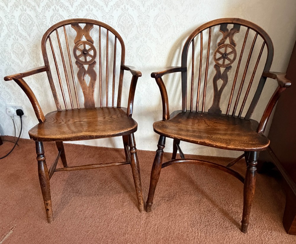 A near pair of wooden wheelback Windsor armchairs with curved hoops, turned legs, and carved central back splats. View II