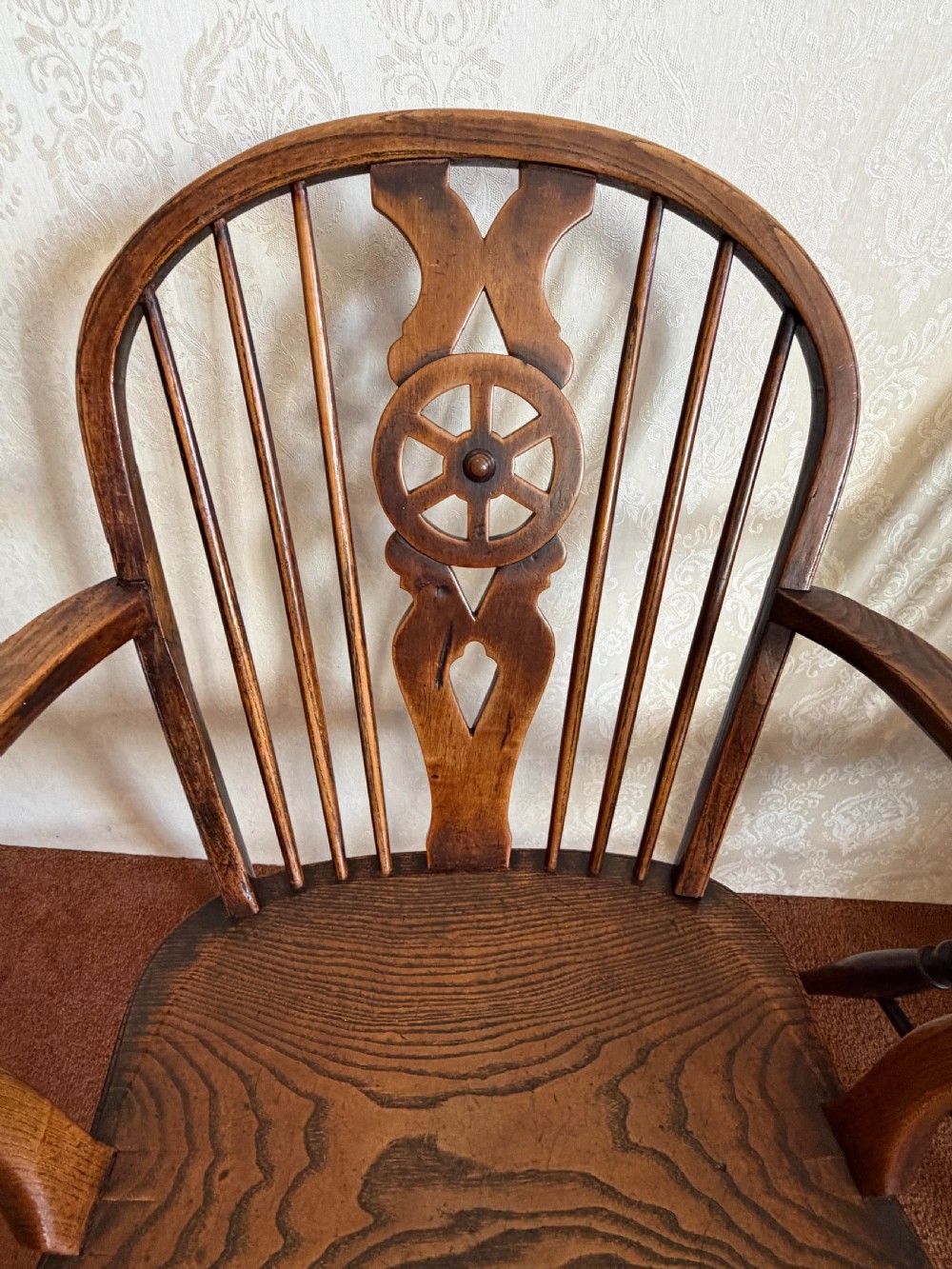 A near pair of wooden wheelback Windsor armchairs with curved hoops, turned legs, and carved central back splats. View V