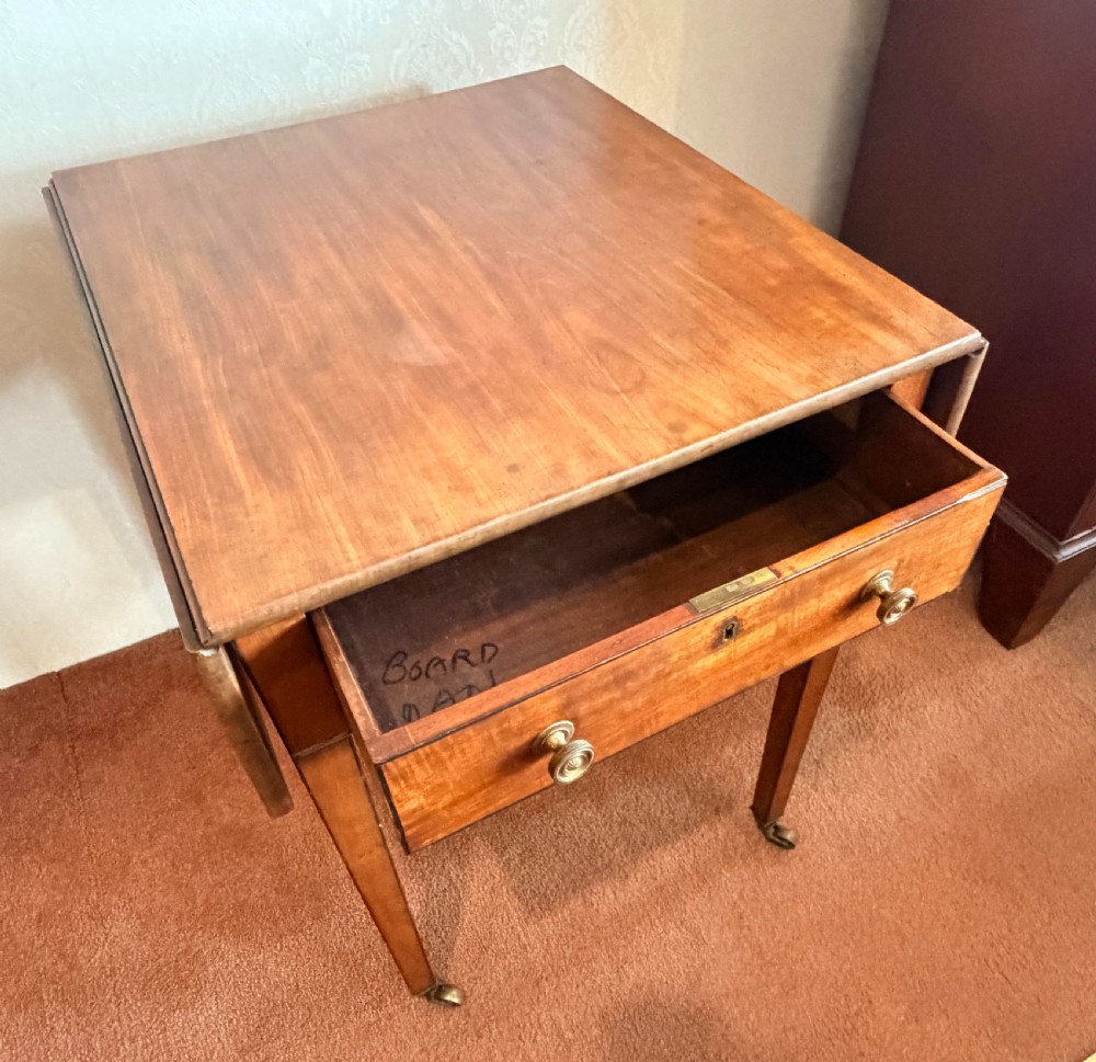 A Georgian mahogany Pembroke side table featuring two hinged drop leaves, a single drawer with brass knobs, string-inlaid square tapered legs, and brass castors. View III