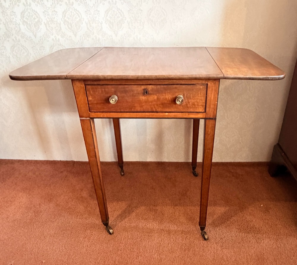 A Georgian mahogany Pembroke side table featuring two hinged drop leaves, a single drawer with brass knobs, string-inlaid square tapered legs, and brass castors. View IV