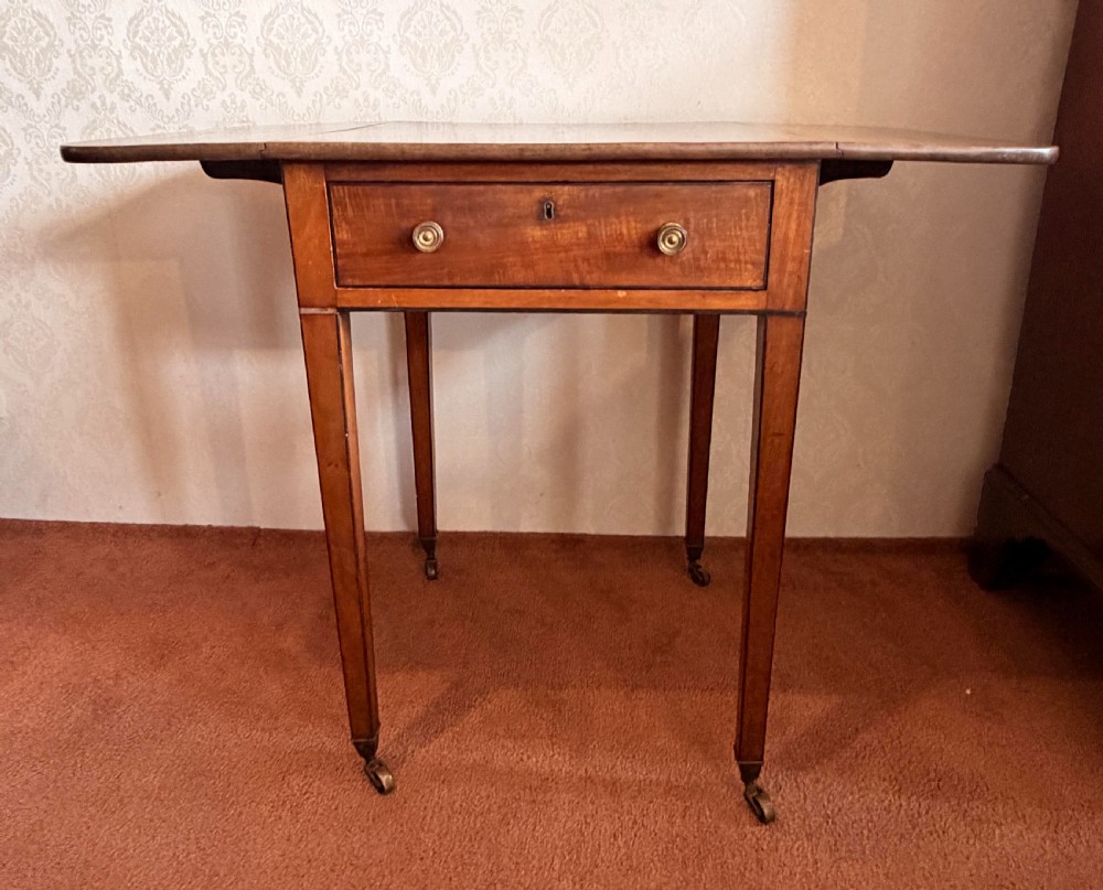 A Georgian mahogany Pembroke side table featuring two hinged drop leaves, a single drawer with brass knobs, string-inlaid square tapered legs, and brass castors. View V