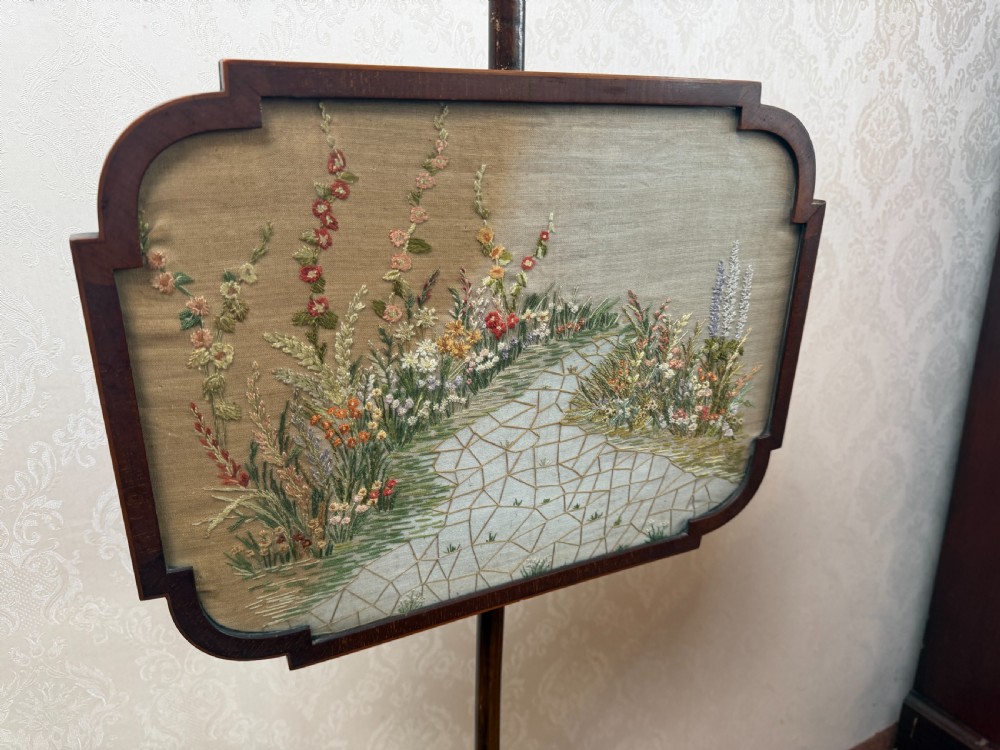 A mahogany pole screen featuring a slender turned shaft on a tripod cabriole base with an adjustable framed embroidered panel depicting a garden path. View III
