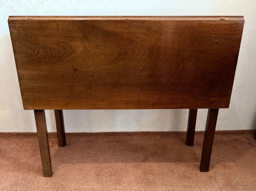 A mahogany drop leaf table shown in the folded position with straight legs and a dark timber finish.