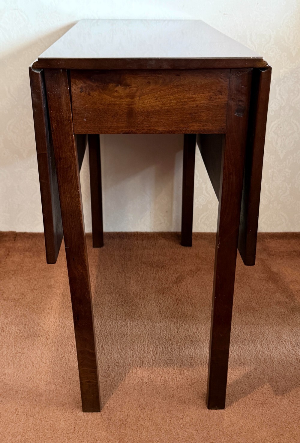 A mahogany drop leaf table shown in the folded position with straight legs and a dark timber finish. View II