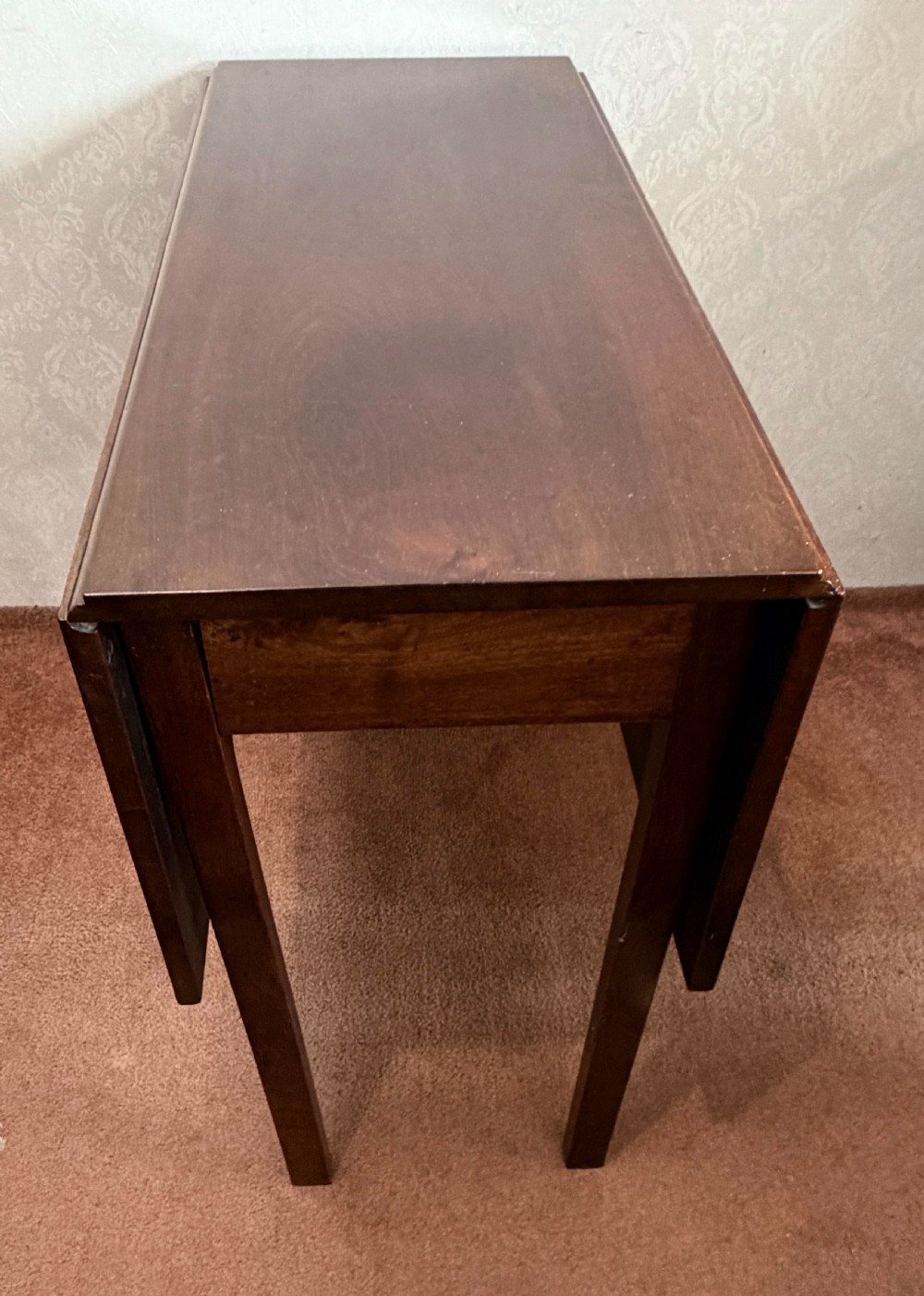 A mahogany drop leaf table shown in the folded position with straight legs and a dark timber finish. View IV