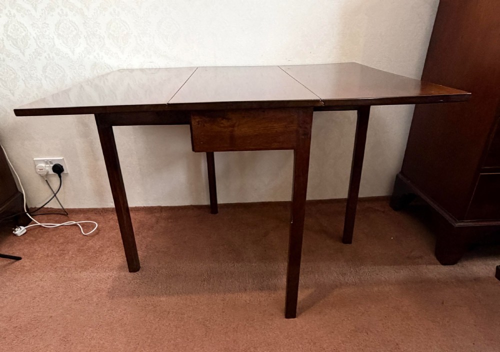 A mahogany drop leaf table shown in the folded position with straight legs and a dark timber finish. View V