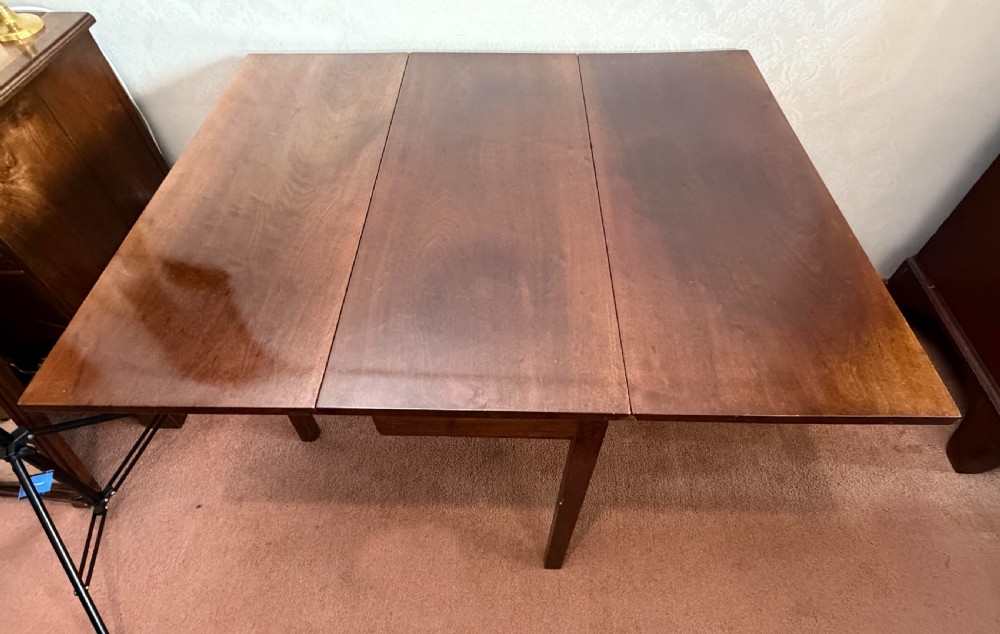 A mahogany drop leaf table shown in the folded position with straight legs and a dark timber finish. View VI