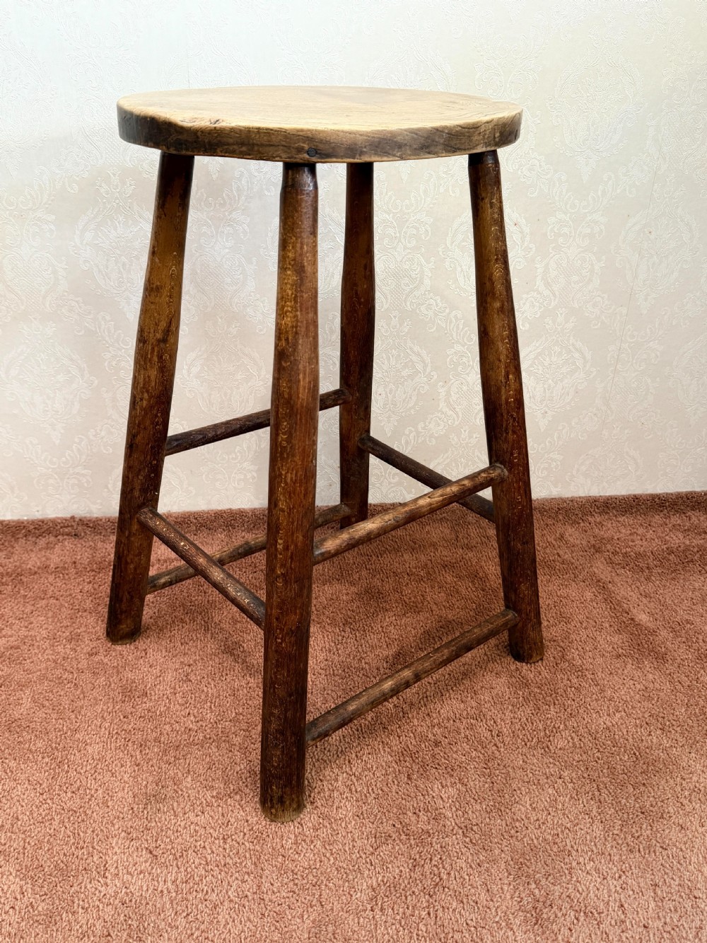 A rustic vintage ash stool featuring a circular solid wood seat mounted on four tapered turned legs joined by simple side stretchers. View IV