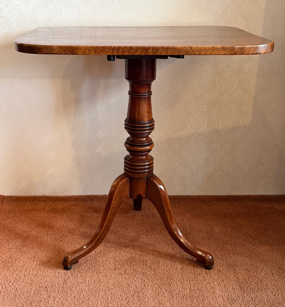 A Georgian mahogany tripod table featuring a rounded rectangular tilt-top surface, a ring-turned central pedestal, and three downswept legs.