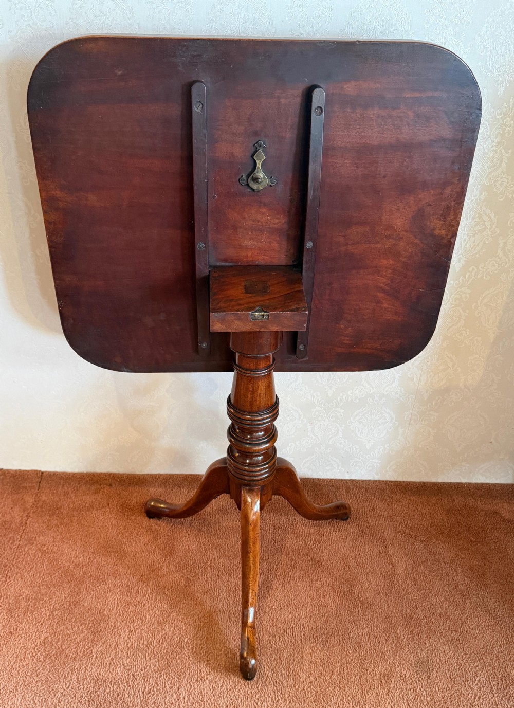 A Georgian mahogany tripod table featuring a rounded rectangular tilt-top surface, a ring-turned central pedestal, and three downswept legs. View III