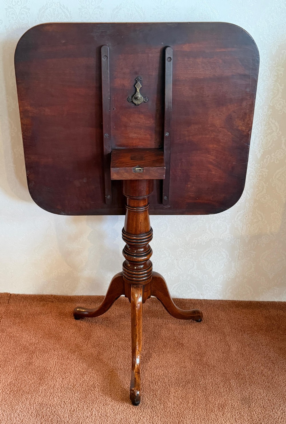 A Georgian mahogany tripod table featuring a rounded rectangular tilt-top surface, a ring-turned central pedestal, and three downswept legs. View V