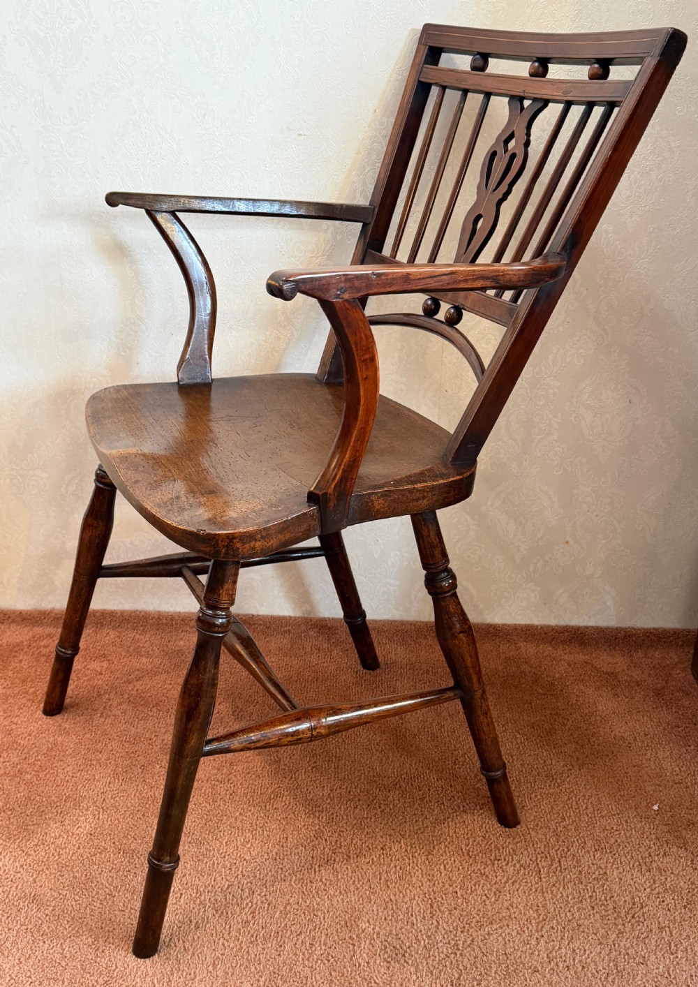 An antique wooden Mendlesham armchair featuring a square back with spindles, spherical bead details, a central pierced splat, curved arms, and a contoured wooden seat. View III