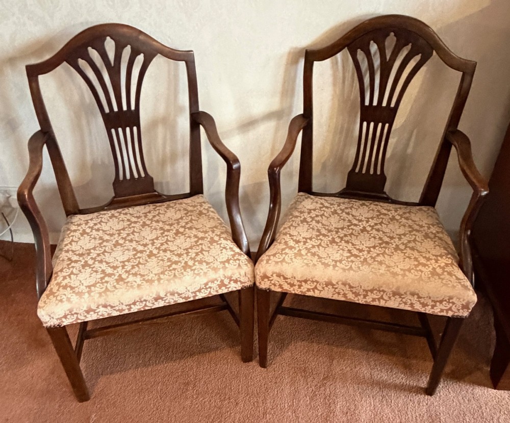 A pair of mahogany Hepplewhite style armchairs featuring carved pierced splats and patterned upholstered drop-in seats.