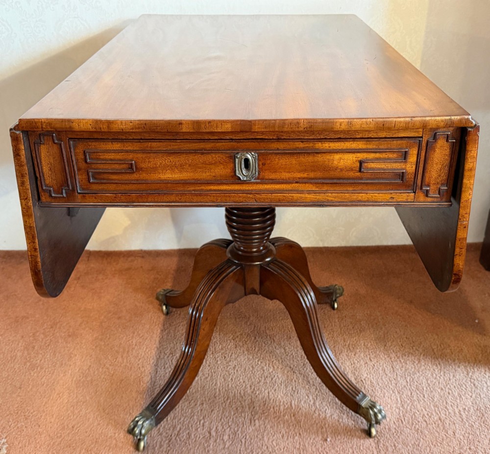 A Regency mahogany drop leaf breakfast table with a reeded central pedestal support and four splayed sabre legs with brass paw castors. View II
