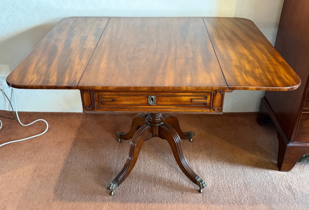 A Regency mahogany drop leaf breakfast table with a reeded central pedestal support and four splayed sabre legs with brass paw castors. View III