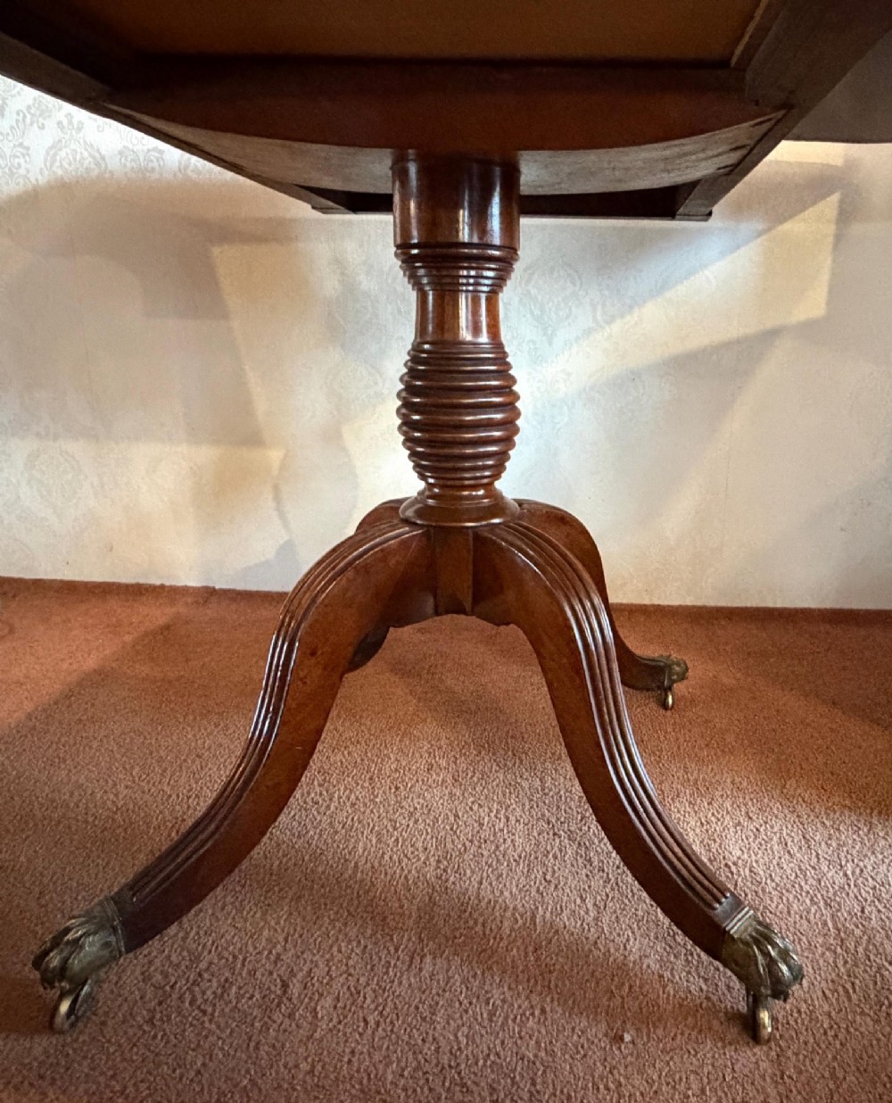 A Regency mahogany drop leaf breakfast table with a reeded central pedestal support and four splayed sabre legs with brass paw castors. View IV