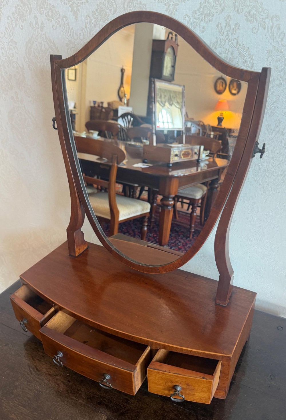 A Georgian style mahogany toilet mirror with a shield-shaped swivel frame set above a bow-fronted base containing three small drawers with brass handles. View III