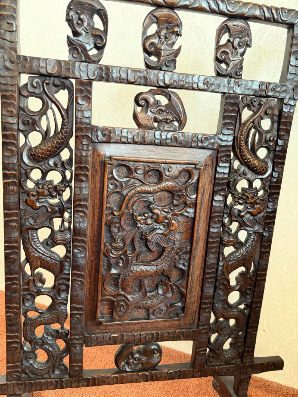 A dark carved hardwood freestanding screen featuring openwork dragon motifs and a central relief panel on carved feet. View IV