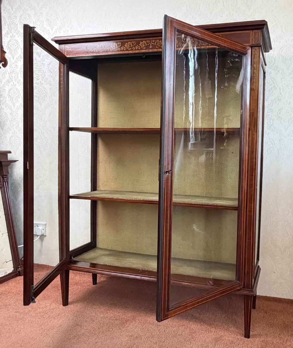 A late nineteenth-century mahogany display cabinet featuring twin glazed doors, floral marquetry frieze inlay, glass side panels, and square tapered legs. View III